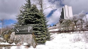 A sign reading "Sugartop" with a snow-covered landscape and a tall building in the background. - 2017 Top Floor Condo Of SugarTop Resort w/ Pool, Hot Tub, Breathtaking Views (Sugar Mountain)