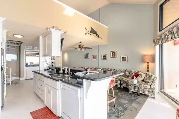 Une cuisine moderne dotée d’un îlot central, de meubles blancs et d’un ventilateur de plafond.