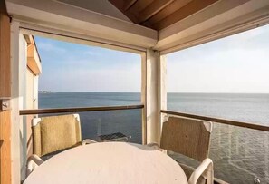 Un espace extérieur abrité, avec une table et deux chaises, donnant sur une étendue d’eau.