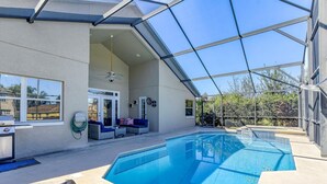 A covered outdoor swimming pool with a glass ceiling, a ceiling fan, and a seating area with sofas. - Large Home near Theme Parks with Pool, Spa and Pets Welcome! (Kissimmee)