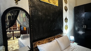 A hotel room with a bed, a mirror, a painting, and a decorative wall. - RIAD ABQARI YOUSSEFI (Fes)