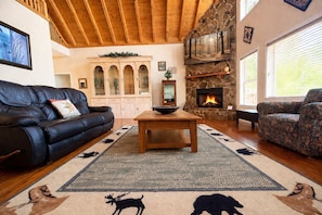 A cozy living room with a fireplace, leather sofas, a dining table, and a stone wall. - Stone's Mountain View (Altamont)