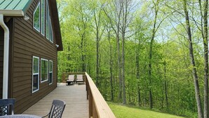 A wooden deck with two chairs and a table, surrounded by a forest. - Stone's Mountain View (Altamont)