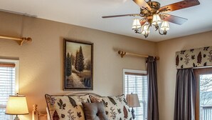 A bedroom with a wooden bed, a nightstand, a lamp, a ceiling fan, and a painting on the wall. - Stone's Mountain View (Altamont)