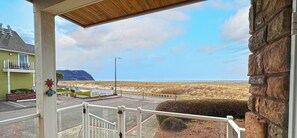 A balcony with a view of the beach and a distant mountain.