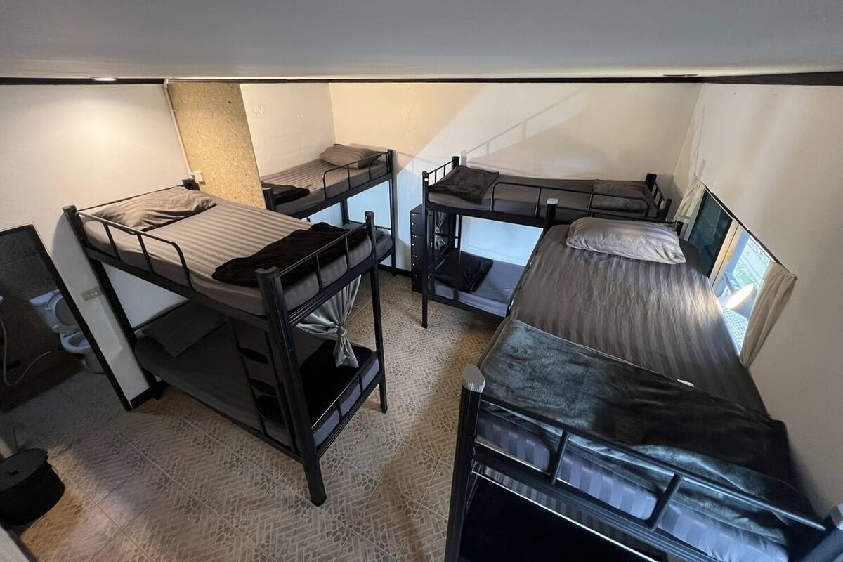 Habitación tipo dormitorio con literas, un escritorio pequeño y ventana que proporciona luz natural.