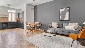 En moderne stue med en grå sofa, et sofabord og et spiseområde med stole og et bord.