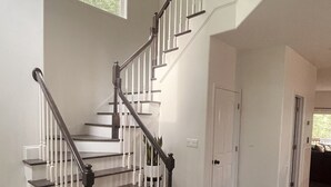 A staircase with white railings and dark steps, leading to a landing with a door.