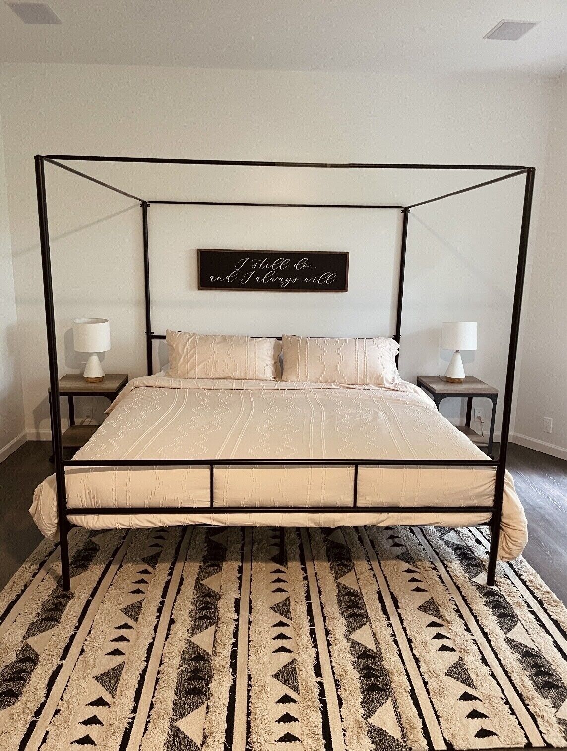 Una cama con dosel y un cartel decorativo encima.