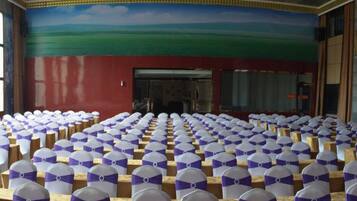 A large hall with rows of chairs, each with a white cover and a purple ribbon.