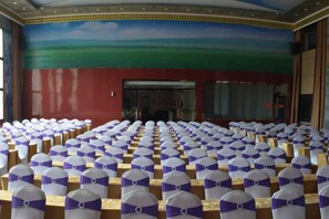 Une grande salle avec des rangées de chaises, chacune recouverte d’une housse blanche et ornée d’un ruban violet.