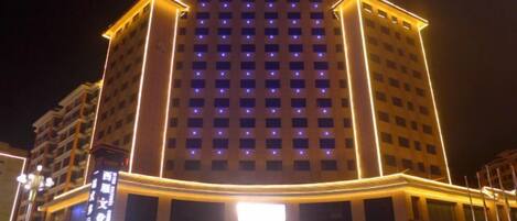 A multi-story hotel with a prominent entrance and illuminated signage.
