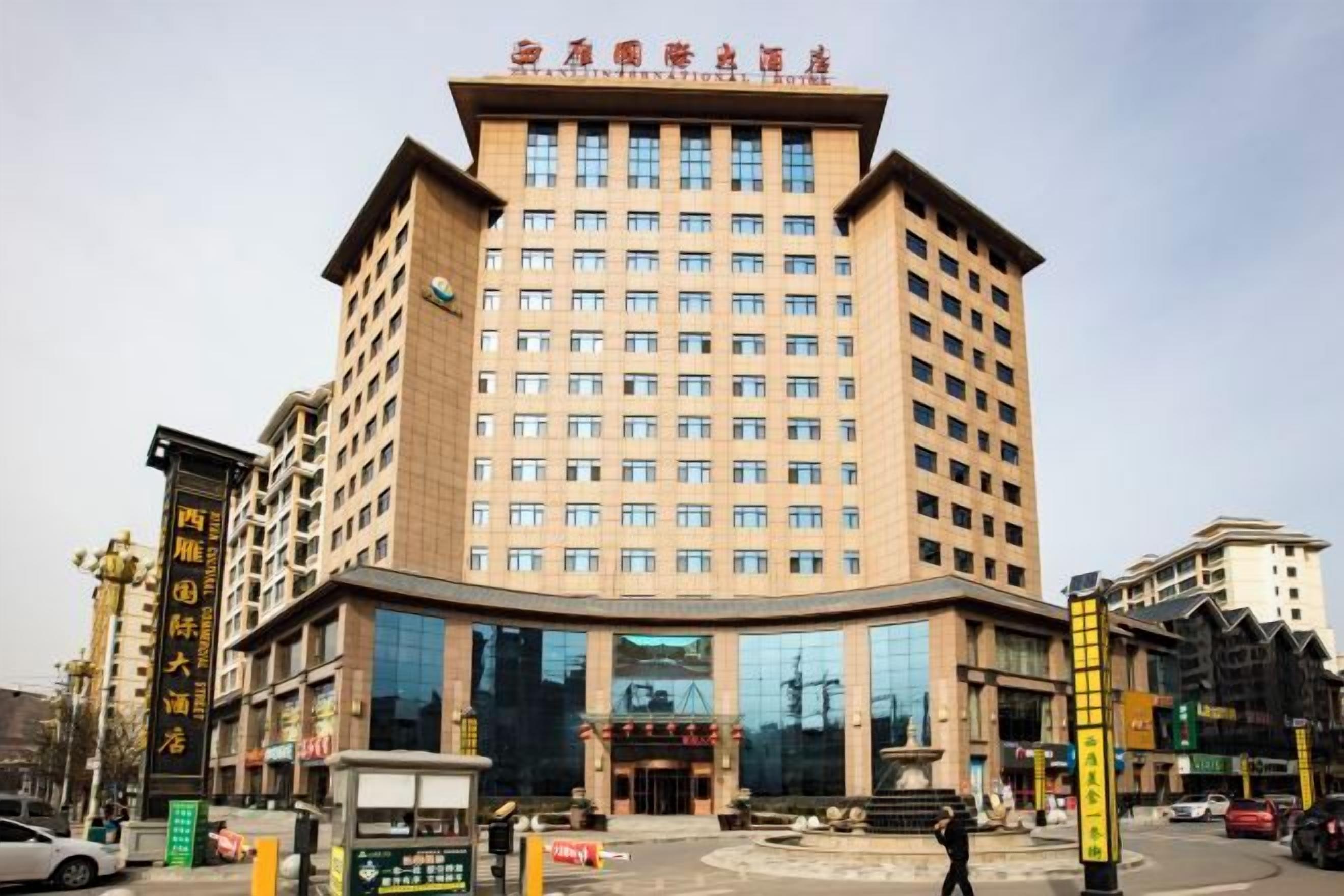 A multi-story hotel with a prominent entrance, large windows, and a central courtyard.