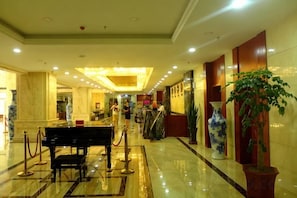 A hotel lobby with marble flooring, a reception desk, a piano, and a large vase. - Xiyan International Hotel (Huining)