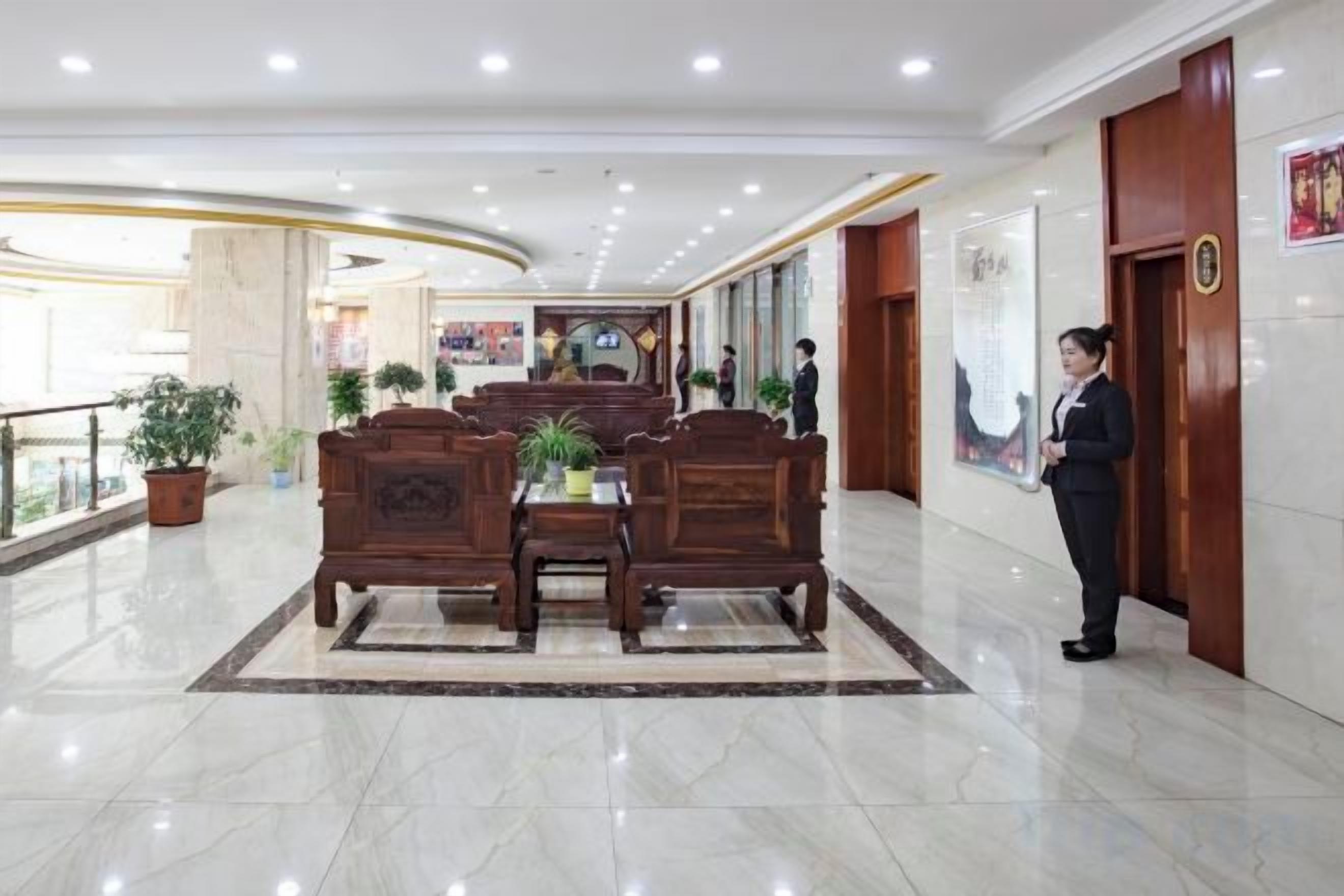 Un hall de hotel con mostrador de recepción, zona de estar y recepcionista.