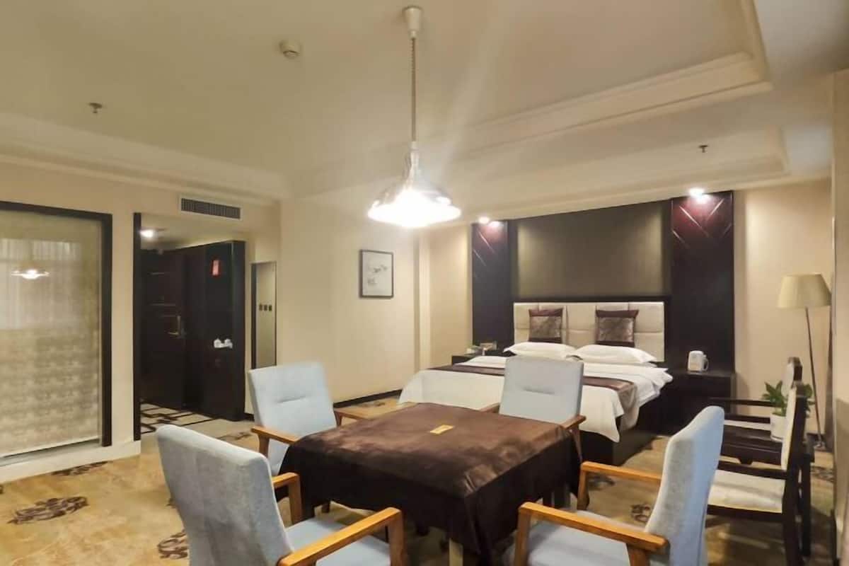 A hotel room with a bed, a desk, a chair, and a table.