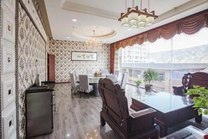 Un coin repas avec une table et des chaises, un réfrigérateur et un mur décoré d’un motif.