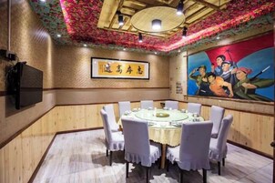 A dining area with a round table, chairs, and a mural on the wall.