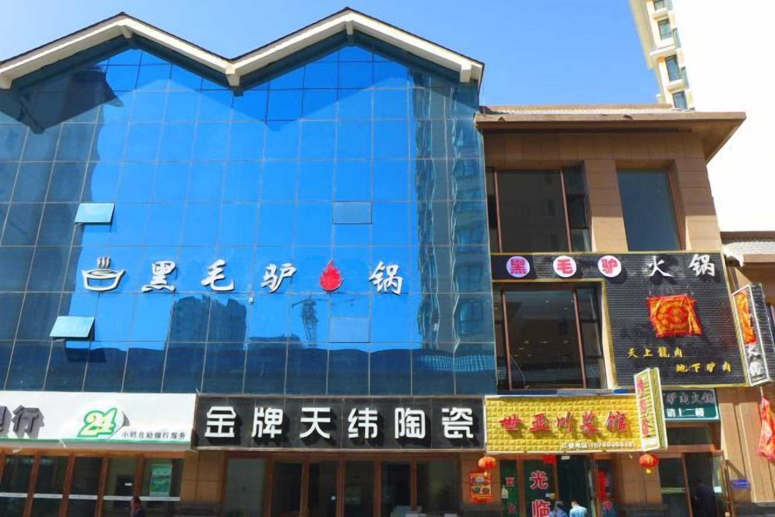 Un immeuble doté d’une façade en verre bleu et de nombreuses enseignes indiquant différents commerces.