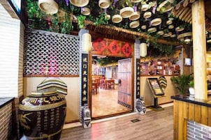 An interior with a traditional Asian design, featuring a wooden floor, decorative ceiling elements, and a reception area with a counter and seating.