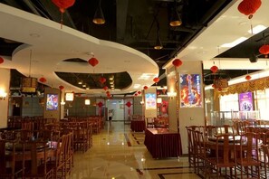 Un restaurant doté de nombreuses tables et chaises, d’un plafond voûté et de lanternes rouges.