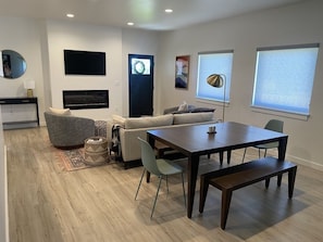 Relax in this stylish living room with a sofa, dining table, and fireplace.
