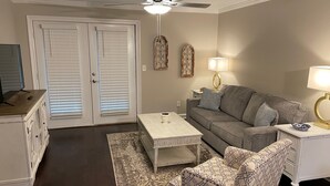 A living room with a gray sofa, patterned armchair, white coffee table, and a ceiling fan. - Walk to Ole Miss Games, Oxford Square - 2 Master Suites - Patio - Near Stadium! (Oxford)