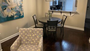 A dining area with a round table, four chairs, a hanging light fixture, and a painting on the wall. - Walk to Ole Miss Games, Oxford Square - 2 Master Suites - Patio - Near Stadium! (Oxford)