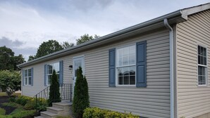 Ein zweistöckiges Haus mit Veranda, Treppe und einem gepflegten Garten.