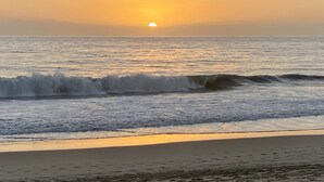 Ein Strand mit Wellen und einem Sonnenuntergang.