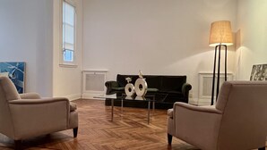 A spacious living room with a herringbone-patterned hardwood floor, two armchairs, a coffee table, and a large area rug. - Beautiful apartment in the heart of Buenos Aires Art (CABA)