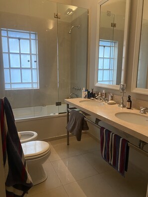 Une salle de bain moderne avec une douche à parois de verre, des toilettes, un lavabo avec un miroir et des serviettes accrochées au mur.