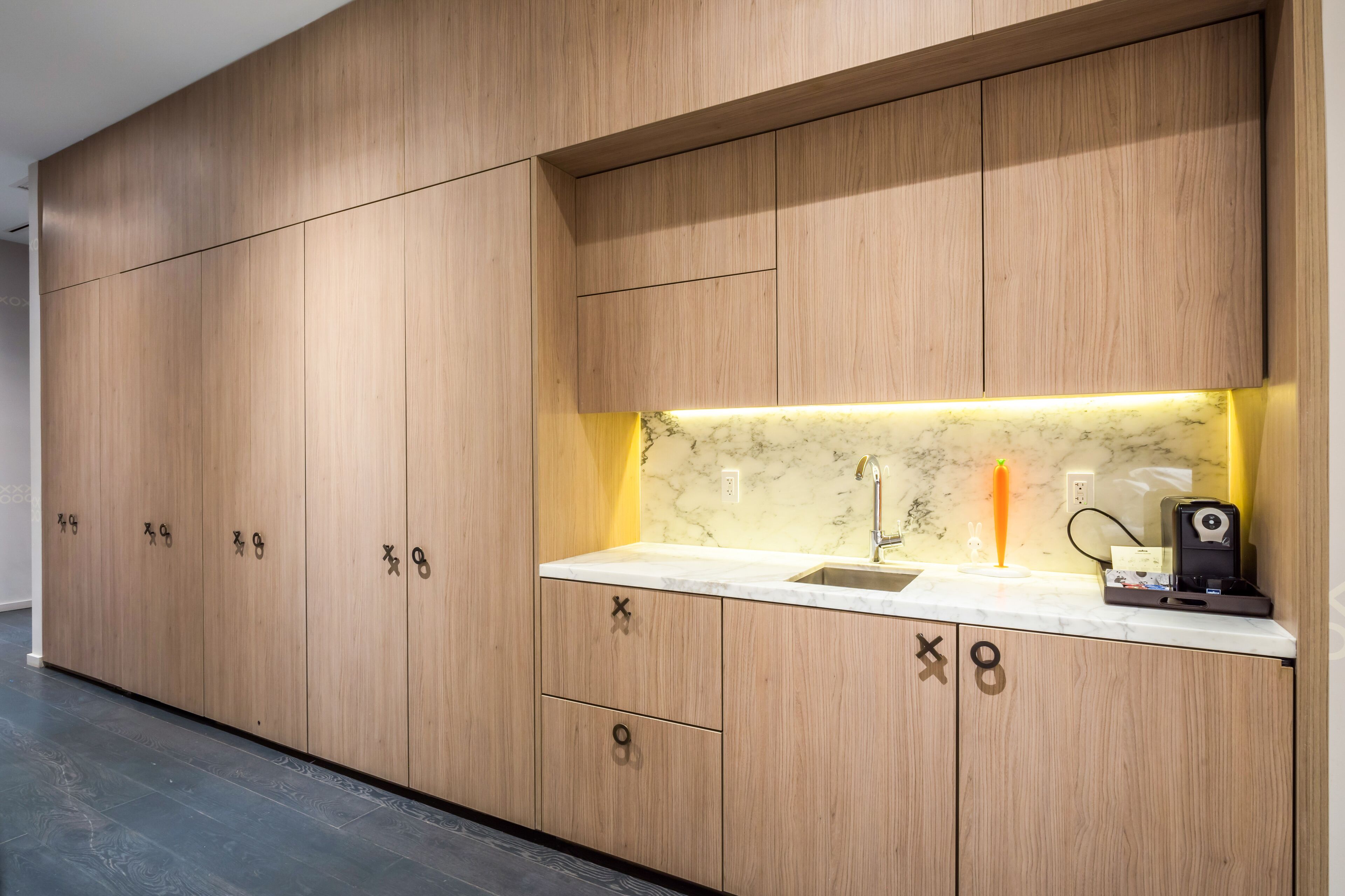 A modern kitchen with wooden cabinets, a marble countertop, and a built-in sink.