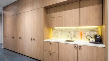 A modern kitchen with wooden cabinets, a marble countertop, and a built-in sink.