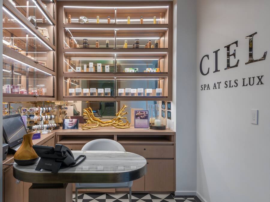A modern spa area with shelves of products, a reception desk, and a wall sign reading "Ciel SPA AT SLS LUX".
