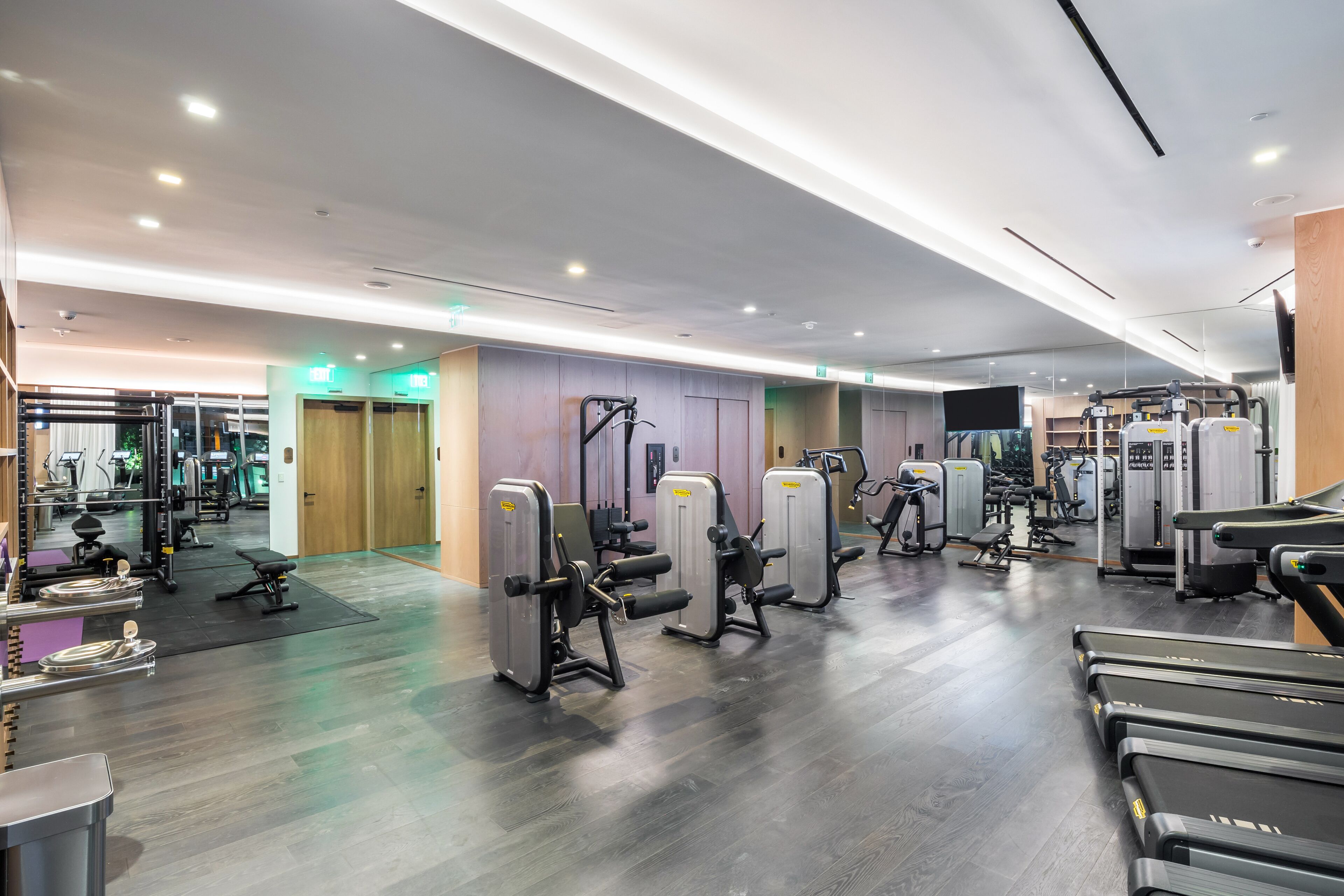 A modern gym with treadmills, weight machines, and a mirrored wall.
