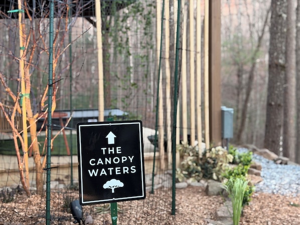 Un panneau avec une flèche pointant vers le haut et le texte « THE CANOPY WATERS », ainsi qu’une icône représentant un arbre.