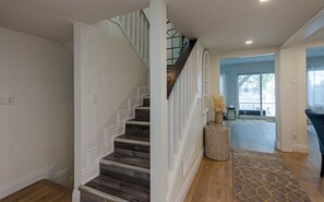 Eine Treppe mit Holzbodenstufen und weißen Geländern führt zu einer Zwischenebene mit einem gemusterten Teppich und einer Ziervase.