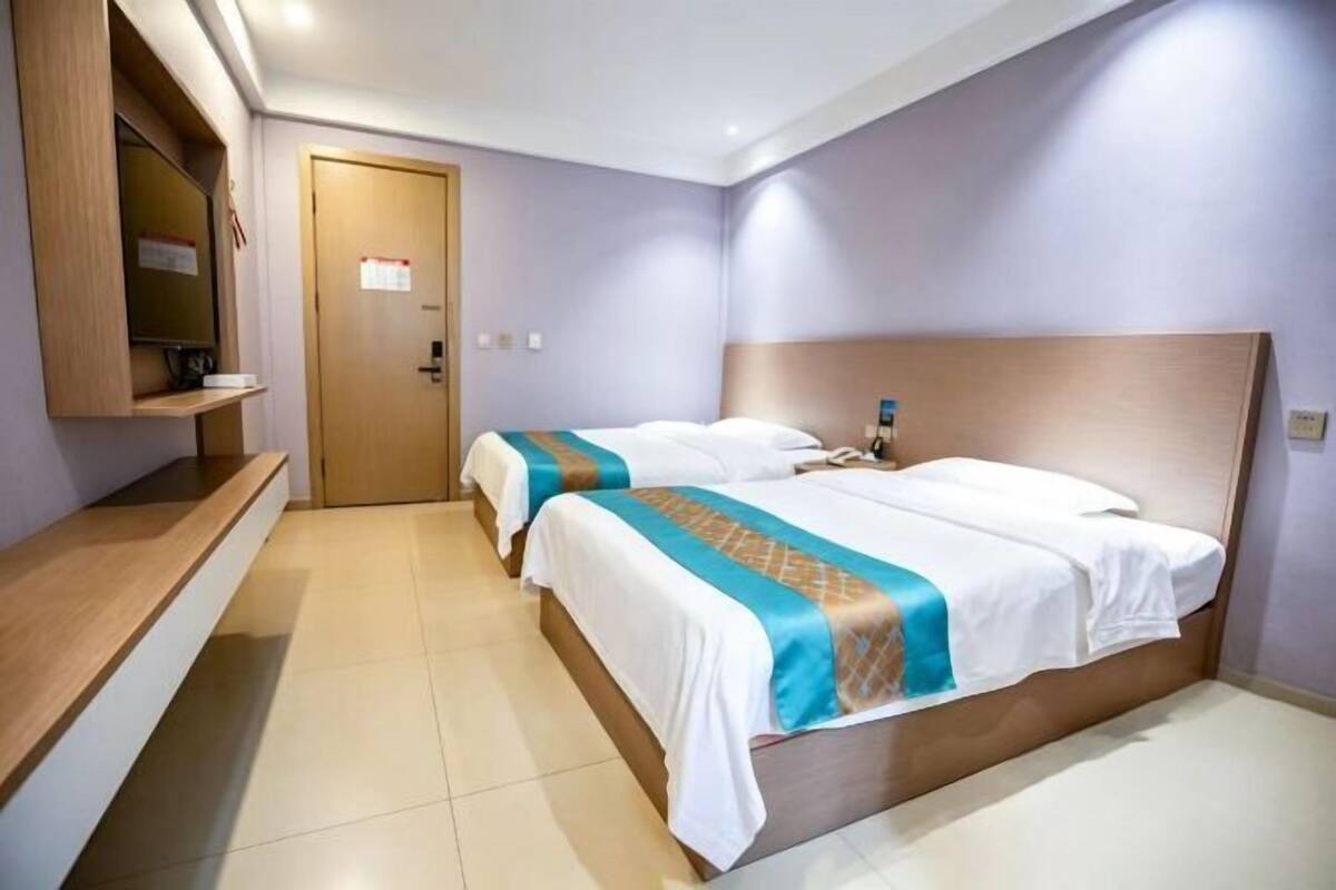 A hotel room with two beds, a wooden headboard, a bedside table, and a mirror.