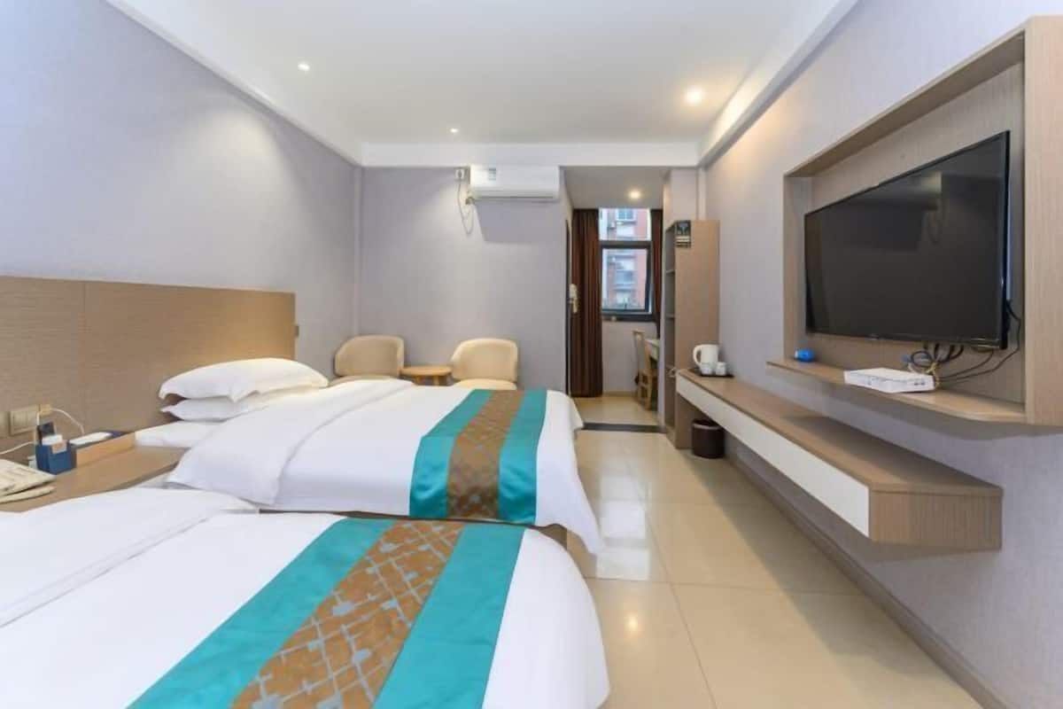 A hotel room with two beds, a TV, a desk, and a chair.
