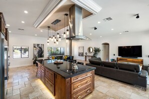 A spacious living area with a large island, a modern kitchen, and a flat-screen TV.