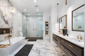 A modern bathroom with a marble floor, a large bathtub, a walk-in shower, and a vanity with a mirror.