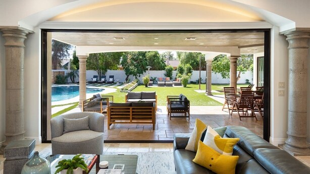 A spacious living area with a view of a backyard, including a pool and outdoor furniture. - Resort-Style Escape with Heatable Pool, Games & Modern Design (Scottsdale)