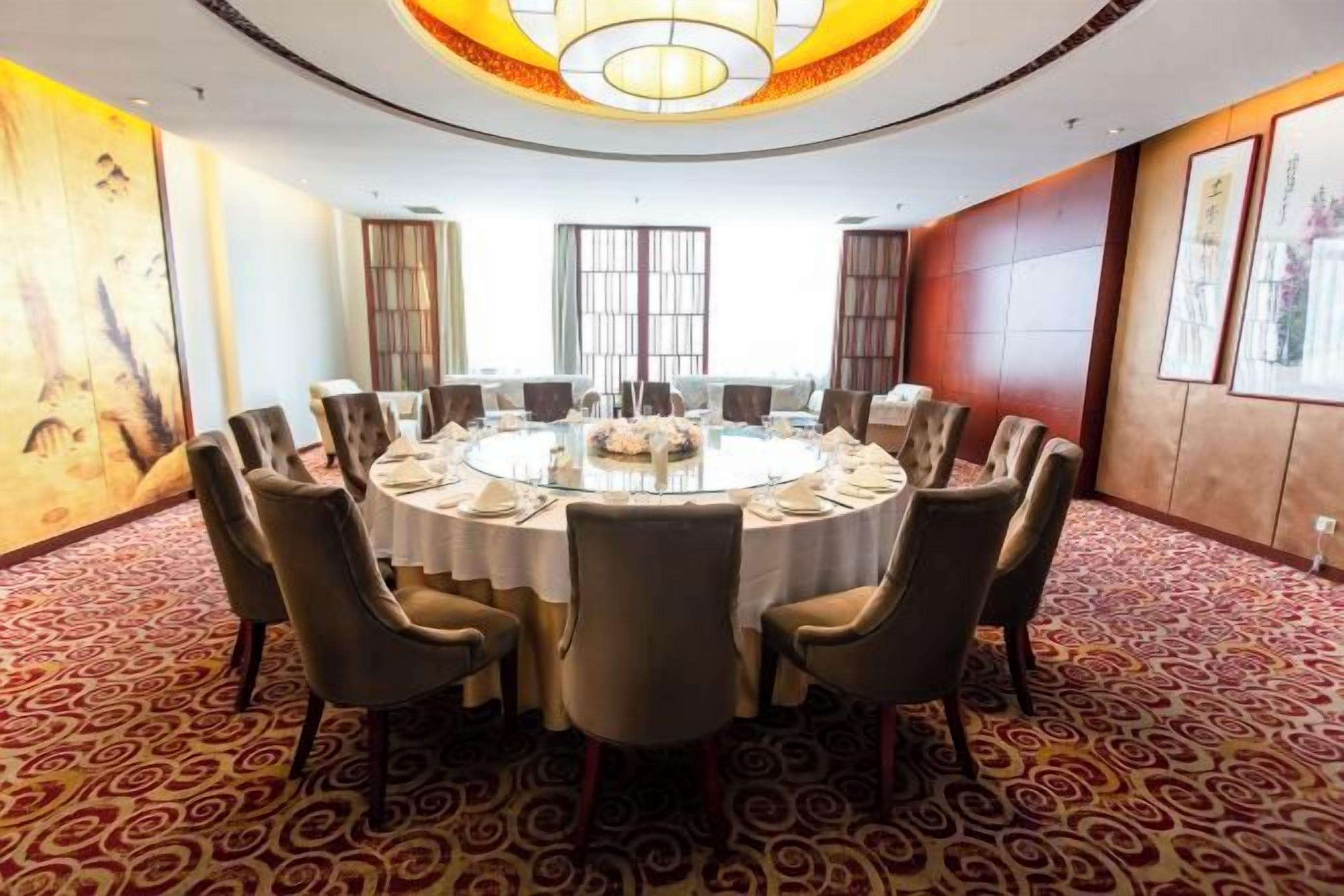 A conference room with a round table, chairs, and a chandelier.