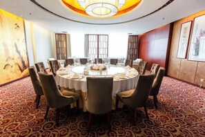 Sala de conferências com mesa redonda, cadeiras e lustre.