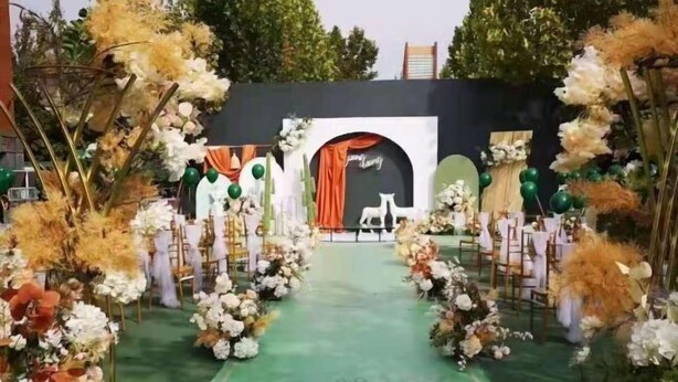 A decorated aisle with floral arrangements and a green carpet. - University Hotel (Binzhou)