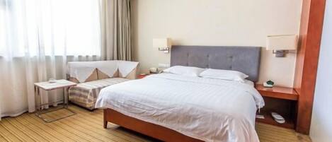 A hotel room with a bed, bedside tables, a nightstand, a lamp, and a window with curtains.