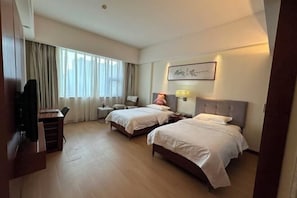 A hotel room with two beds, a desk, a chair, a TV, and a window with curtains. - University Hotel (Binzhou)