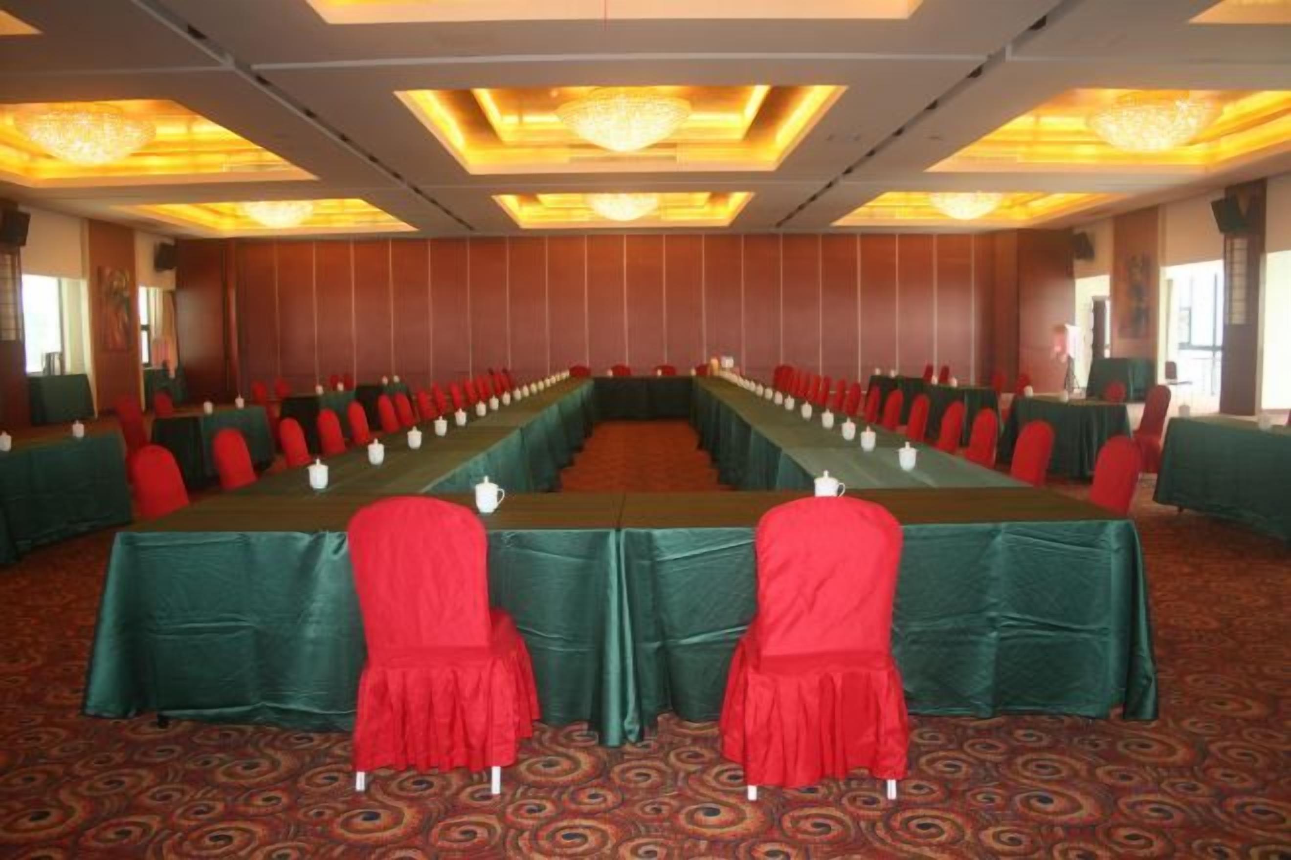 A conference room with a long table, red chairs, and green tablecloths.
