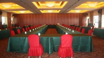 A conference room with a long table, red chairs, and green tablecloths.